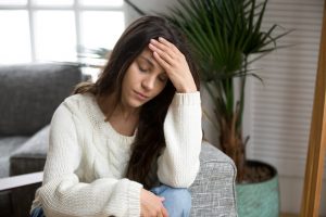 Anxious young woman sitting on the couch with her head in her hands before going to Anxiety treatment in Katy, TX or Anxiety therapy in Katy, TX 77494. Therapy in Katy, TX starts with the Counseling Center at Cinco Ranch 