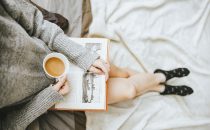woman sitting on the bed drinking coffee practicing self-care