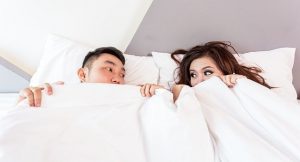 A man and woman laying in bed talking after having sex