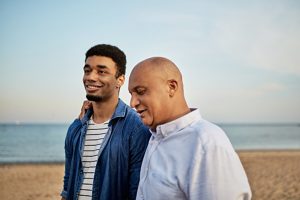 A father and his son walking on the beach and talking. Represents the need for Failure to Launch therapy in Katy, TX 77494