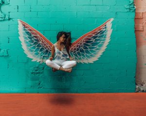 woman sitting in front of a turquoise wall with wings painted behind her, How to Regulate Your Emotions blog, begin counseling today in katy texas at the counseling center at cinco ranch