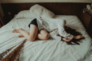 Woman laying in bed seeming defeated, binge eating blog, how to break the binge eating cycle, therapy at the counseling center at cinco ranch, katy texas.