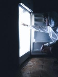 man looking into a refrigerator at night, binge eating blog, how to break the binge eating cycle, therapy at the counseling center at cinco ranch, katy texas.