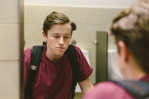 Young male student staring at the sink in the bathroom looking sad, Middle School therapy blog post, katy Texas, 77494.