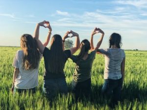 Group of middle school girls using their hands to form hearts in a field, uplifting, Middle School therapy blog post, katy Texas, 77494.