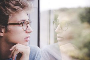 boy or man with glasses starring out the window, thinking, Positive and Negative Self-Talk blog, counseling center at cinco ranch, katy texas 77494