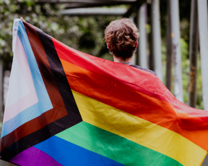 person holding a lgbtqia+ supporting flag who is an ally to the community, sign that spells out gender is a spectrum, What Being an LGBTQIA+ Ally is All About blog, counseling center at cinco ranch, katy Texas 77494